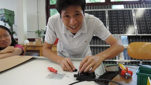 Ein vietnamesischer Berufsschullehrer montiert eine Solaranlage in der Werkstatt der HLFT